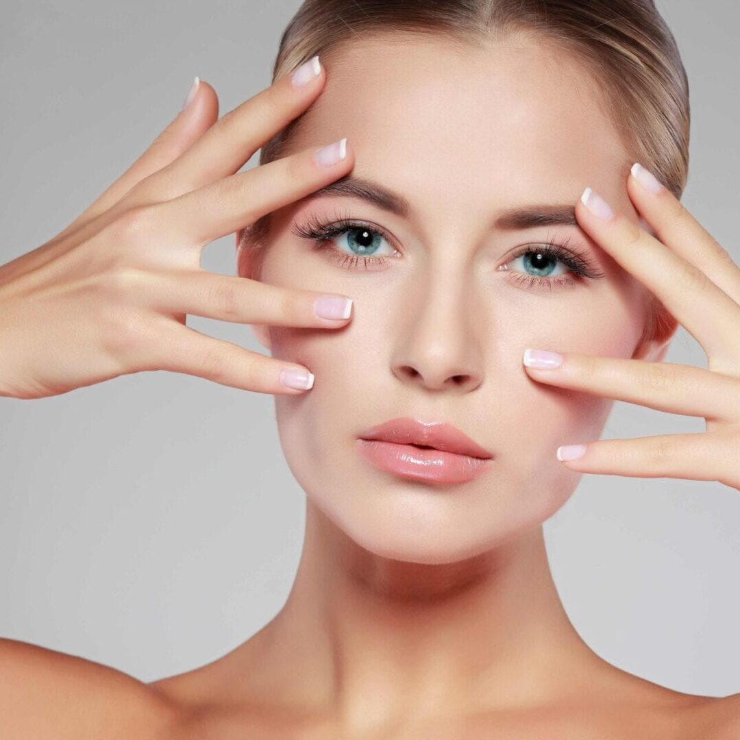 Close-up of a woman with hands framing her face, showcasing clear skin.